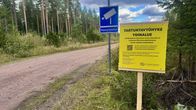 Keltainen kyltti, jolla lukee tartuntavyöhyke. Taustalla on hiekkatie. 