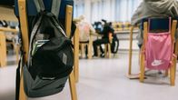 Reppuja roikkuu tuoleilla koululuokassa.