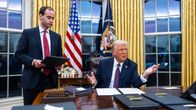 Trump sitter vid skrivbordet i Vita huset och gestikulerar med händerna. 