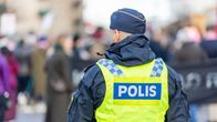 En svensk polis fotograferad bakifrån. Han är klädd i en uniform och en reflexväst där det står "polis".