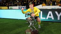 KuPSin pelaaja poseeraa mitali kaulassa pokaalin kanssa kentän laidalla.