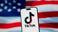 TikTok-logotypen på en mobil mot bakgrunden av USA:s flagga. 