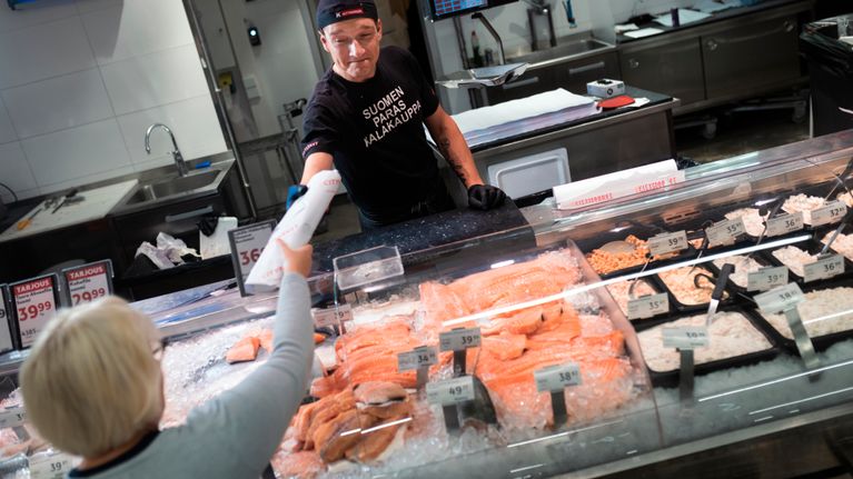 Sellon K-Citymarketin Kalaosaston vastaava Kimmo Pauna ojentaa asiakkaalle ostoksen kalatiskillä. 