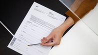 Kelan virkailijan käsi esittelee työttömyystukilomaketta.