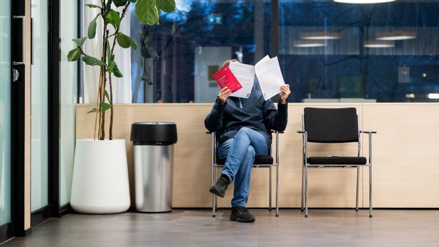 Photo shows a person sitting in an unemployment office.