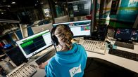 Ylen toimittaja työskentelee radiostudiossa näytön edessä.