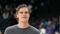 Lauri Markkanen rennossa harmaassa villapaidassa seuraa joukkueensa peliesitystä.