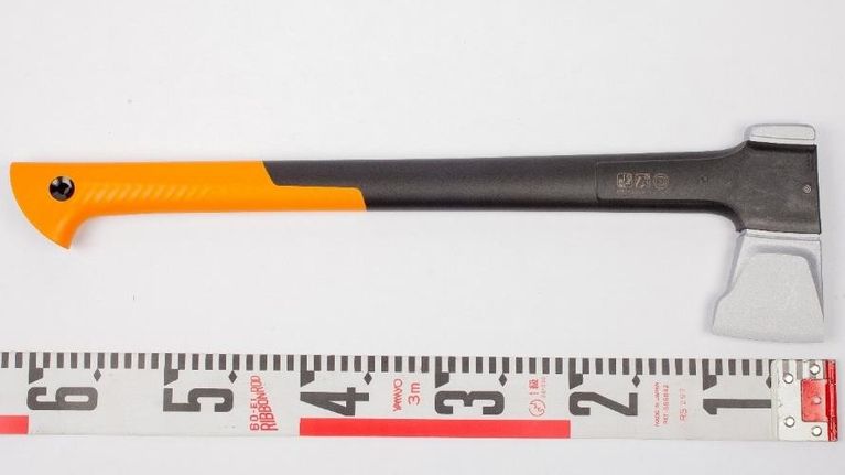 Kuvassa on metrimitan yläpuolella musta kirves, jonka varren pää on oranssi. Kirves on noin 60 senttimetrin mittainen.