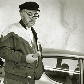 Cafe Veijon baarin toimittaja Jukka Lindfors mikrofoni kädessään Datsun 100A:n vierellä.