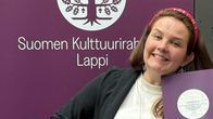 Nainen pitää käsissään apurahan saaja-kylttejä. 