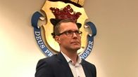 Mies taustallaan kruunuvaakuna.