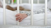 Vauvan käsi puristaa pinnasängyn pinnaa.
