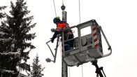 Sähkömies nostokorissa korjaamassa vaurioituneita sähkölinjoja.