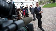 Valtiovarainministeri Jyrki Katainen kävelee toimittajien ja kameramiesten edessä.