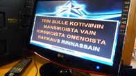 Lähikuvassa karaokelaitteen näytöllä kotiviini-kappaleen sanoja.