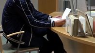 Mies lukee lomaketta sosiaaliviraston palvelupisteessä