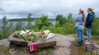 Kaksi tyttöä katsovat Utøyan saarta mantereen puolelta paikasta, johon on tuotu kukkia ja kynttilöitä surmansa saaneiden muistoksi.
