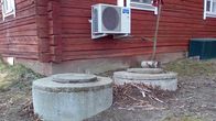 Kuvassa likakaivoja vanhan hirsirakennuksen nurkalla. 