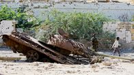 Somalian hallituksen sotilas katselee Afrikan unionin Somalian rauhanturvaoperaation tuhoutunutta tankkia.
