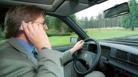 Mies puhuu kännykkään autoa ajaessaan.