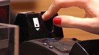 Naisen sormet pistävät maksukortin kortinlukijaan.
