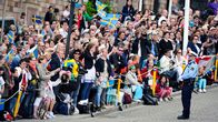Ihmiset heiluttavat Ruotsin lippujen kadun varrella Tukholmassa.
