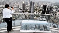 Turisti valokuvaa näköalatasanteella Frankfurtin pankkikeskusta.
