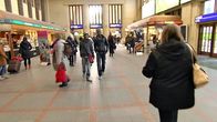 Ihmisiä kävelee Helsingin rautatieaseman sisällä keväisen valon siivittämänä.