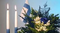 Suomen lippu, itsenäisyyspäivän kynttilöitä ja sinivalkoinen kukka-asetelma.