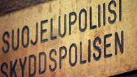 Suojelupoliisi -kyltti talon seinässä.