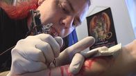 Tatuoija Amon tekee kuvaa asiakkaan käsivarteen.