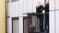 Kaksi naista tupakalla kerrostalon parvekkeella.