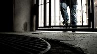Anonyymi mies kävelee pimeään porttikäytävään.