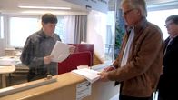 Kuvassa käräjäoikeuden infotiskillä ihmisiä saamassa papereita