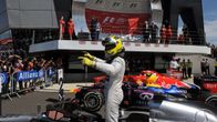 Nico Rosberg tuulettaa Silverstonen osakilpailuvoittoa ajohaalareissa ja -kypärässä autonsa päällä.