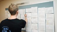Nuori mies tutkii ilmoitustaulua työnhakukeskuksessa Helsingissä.