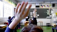 Lapset viittaavat oppitunnilla alakoulussa. 