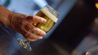 Glass of beer held in a woman's hand.