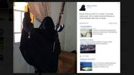 Burkhaan pukeutunut nainen poseeraa aseen kanssa facebook-sivustollaan. 