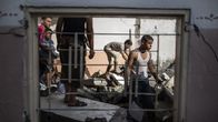 Palestiinalaismiehet etsivät ehjäksi jääneitä tavaroitaan Israelin armeijan pommituksissa tuhoutuneessa kodissaan Gazassa lauantaina.