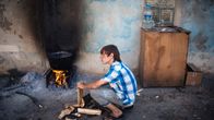 Poika valmisti ruokaa talon edustalla Ukrainan  Avdeevkassa.