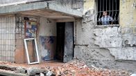 Nainen katsoo ikkunasta yöllisen tuhon jälkiä Donetskissa.