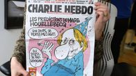 Henkilö näyttää ranskalaisen satiirisen sanomalehden Charlie Hebdon etusivua.