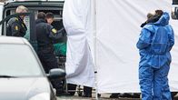 Poliisi siirtää ruumista autoon.