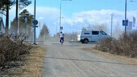 Katupölyä leijailee tiellä, pyöräilijä ajamassa suojatilelle