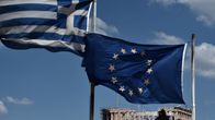 Kreikan ja EU:n liput liehuvat vierekkäin. Takana näkyy Ateenan Akropolis.