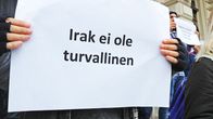 Mielenosoittaja pitää paperia, jossa lukee "Irak ei ole turvallinen" Tampereen Keskustorilla. 