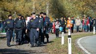 Kaksi poliisia marssii ihmisjoukon kärjessä syksyisellä tiellä. 