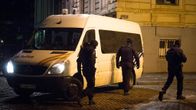 Kolme poliisia valkoisen poliisiauton vieressä.