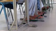Varvastossuisia miesten jalkoja pulpettien alla